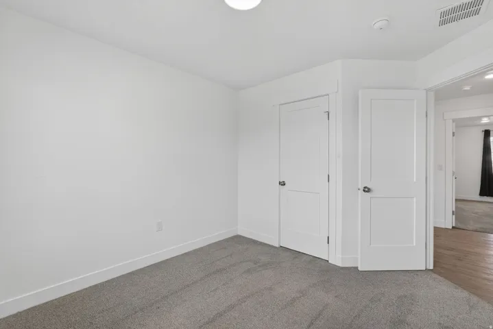 Wall-to-wall carpeting, white interior doors, and overhead flush mount lighting