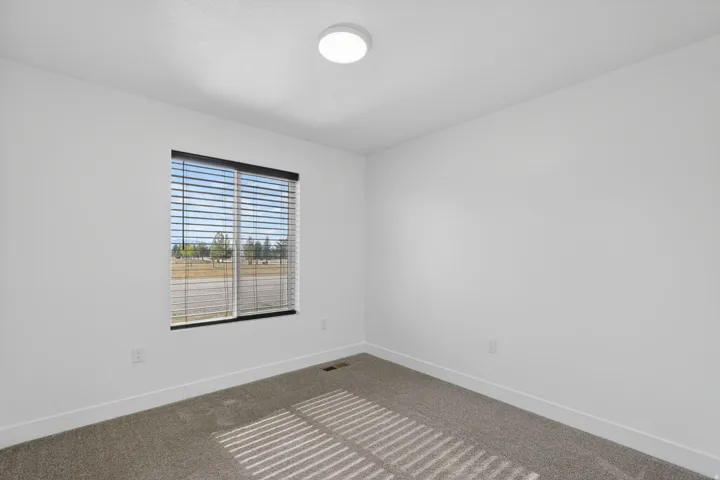 Recessed window with black blinds, light gray wall-to-wall carpeting, and a flush-mount ceiling light fixture