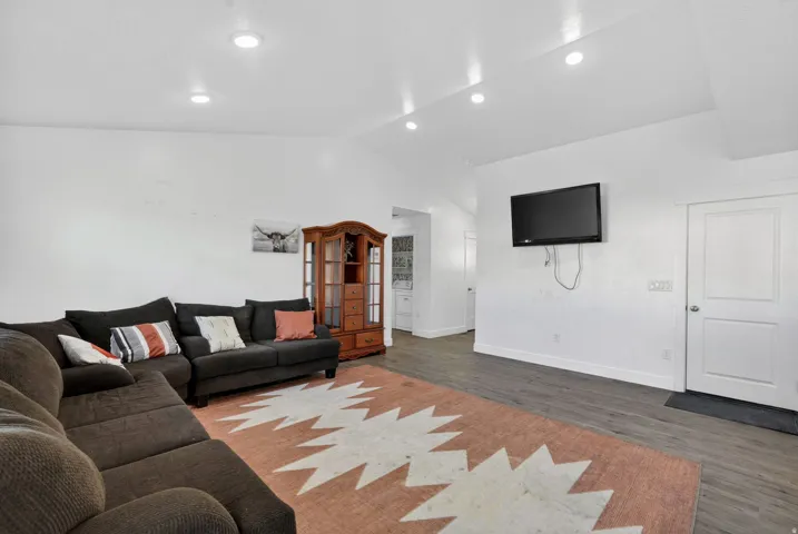 Vaulted ceiling with recessed lighting, light-toned walls, wood-finish flooring, and white trim