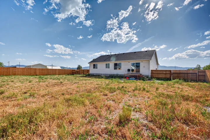 Expansive backyard featuring a wood privacy fence and a rear deck with sliding glass door access