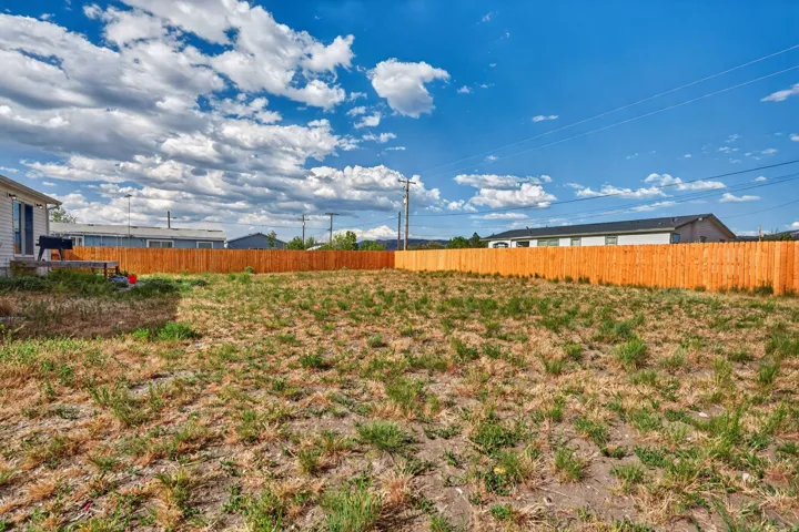 Expansive backyard with a full wood privacy fence and a small patio area