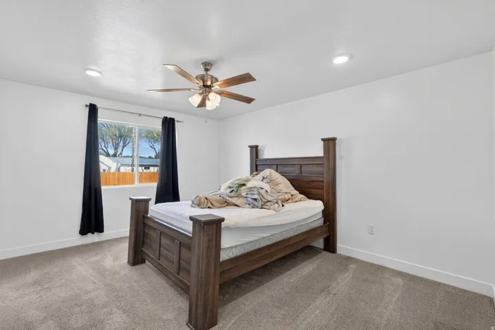 Carpeted flooring, recessed lighting, ceiling fan with integrated light, and large window