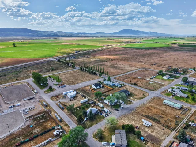 Rural setting with expansive agricultural fields, distant mountain ranges, and residential properties