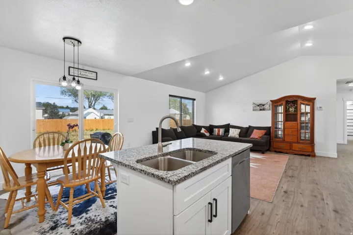 Kitchen island with dual stainless steel sink, granite-style countertop, and white cabinetry