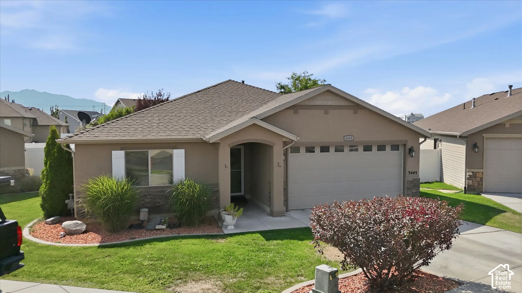 Single-story stucco exterior with stone accents, attached two-car garage, and established front landscaping