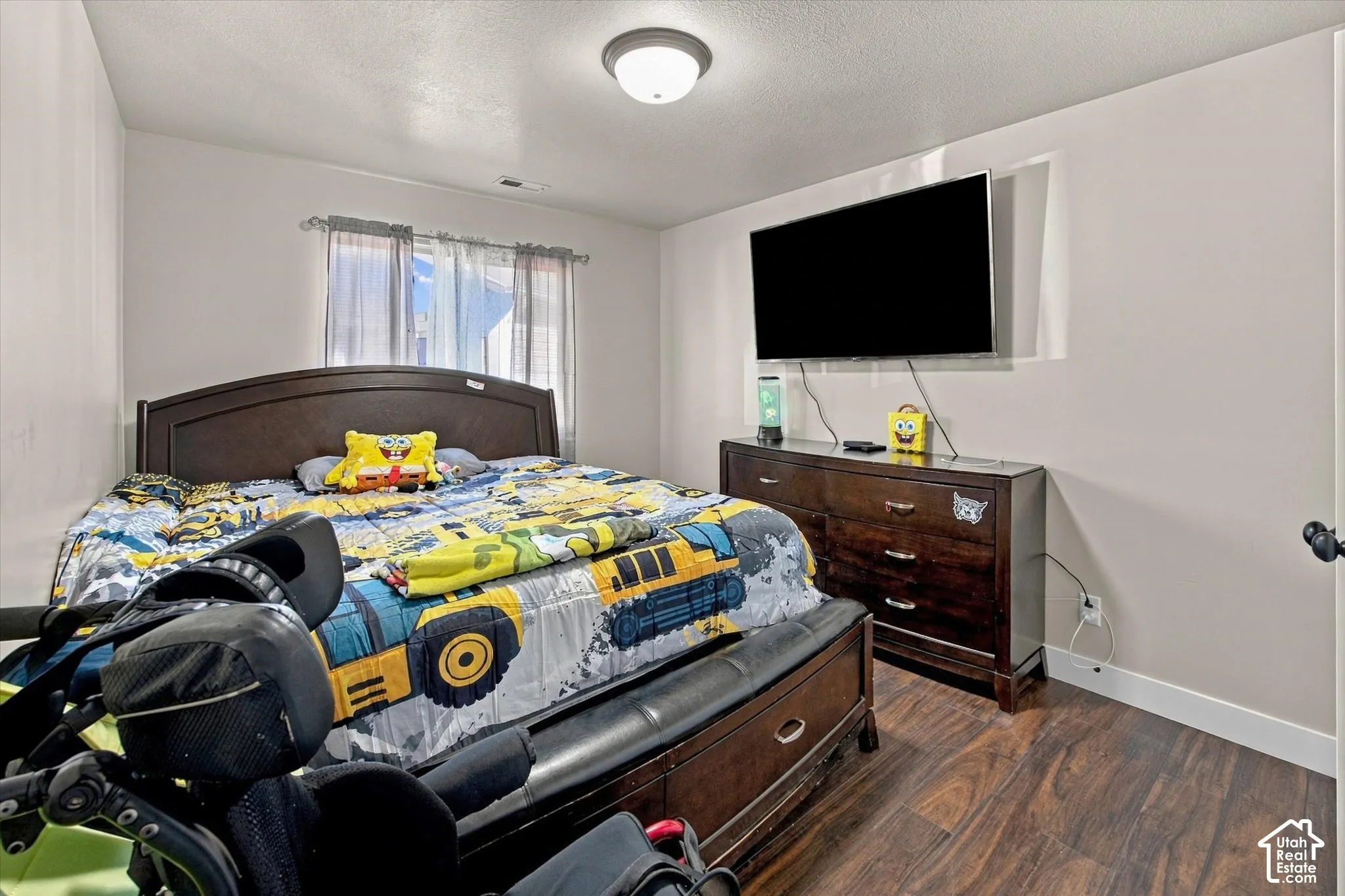Wood-finish flooring with a neutral wall color, featuring a window with natural light and a flush-mount ceiling light fixture