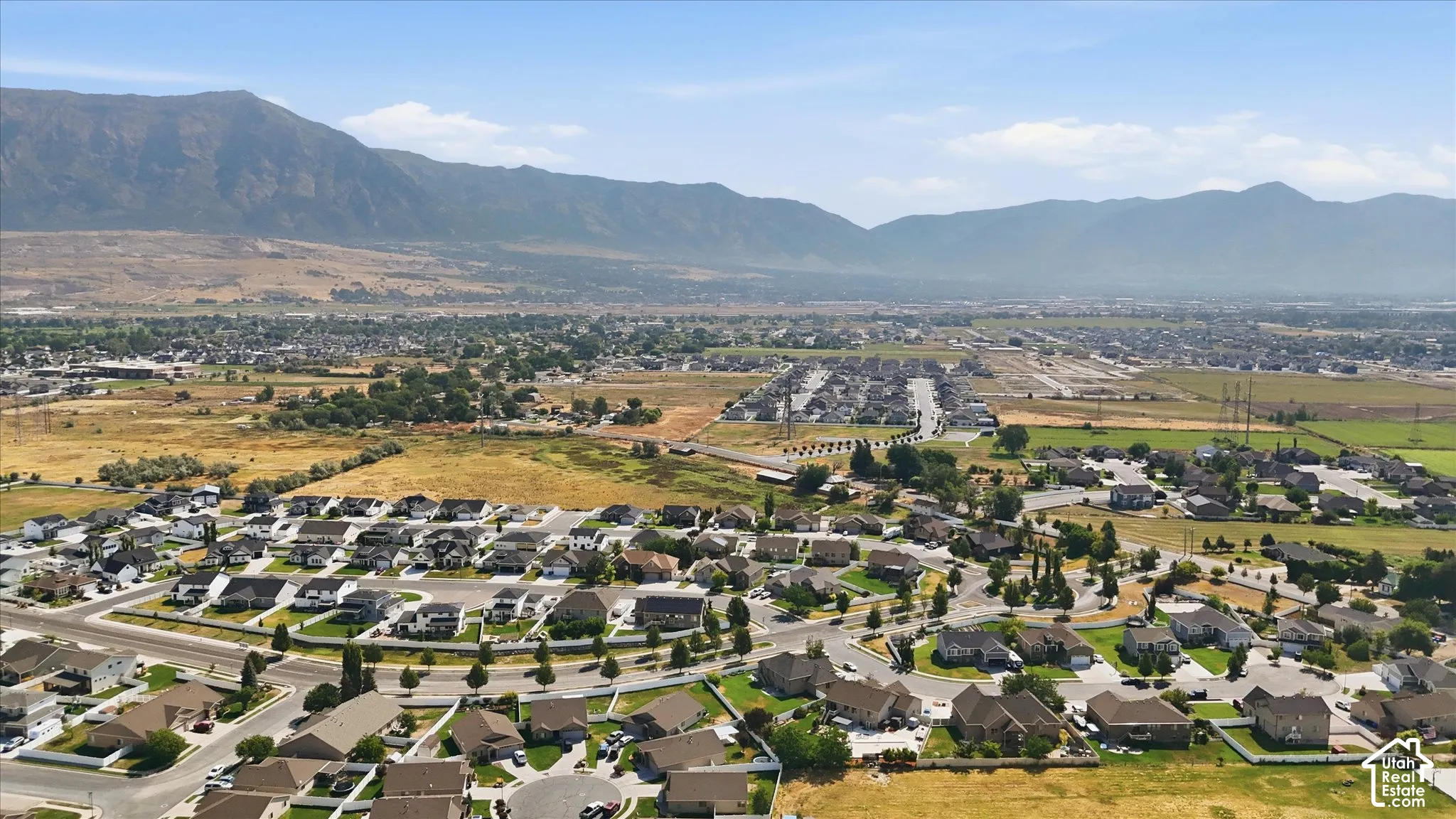 Expansive residential area with numerous single-family homes, surrounded by natural terrain and distant mountains