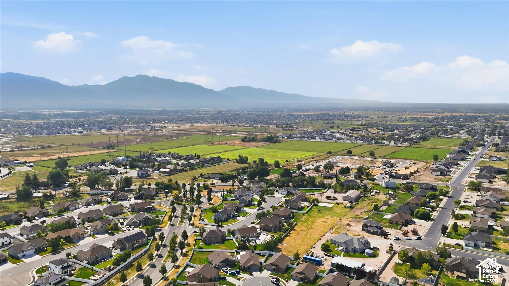 Residential area surrounded by open fields and distant mountains