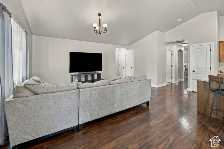 Vaulted ceiling featuring a chandelier, wood-finish flooring, and light gray wall paint