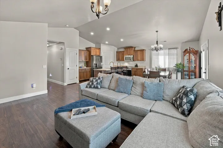 Open concept living area with wood-finish flooring, vaulted ceiling, recessed lighting, and a kitchen featuring wood cabinetry and stainless steel appliances