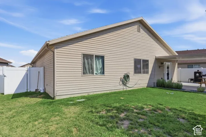 Exterior featuring horizontal siding, white vinyl fencing, a concrete patio, and a covered back entry