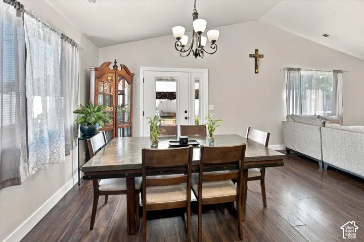 Vaulted ceilings, wood-finish flooring, and a chandelier with opaque glass shades