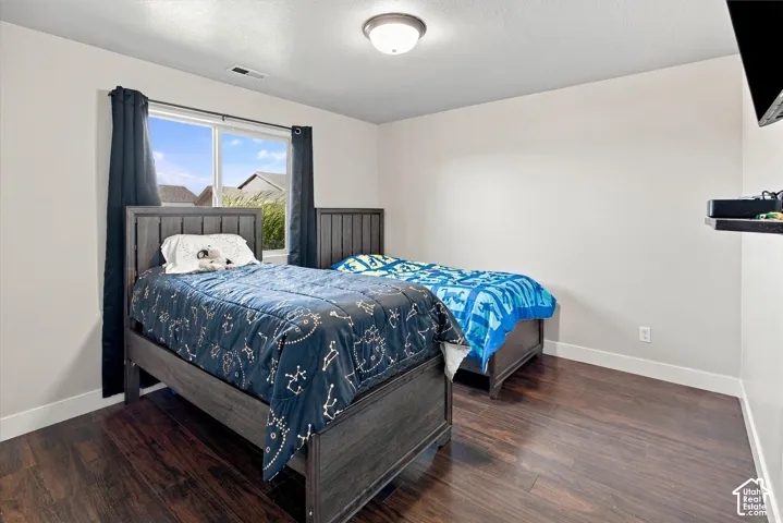 Wood-finish flooring with white baseboards, a window with dark curtains, and a ceiling-mounted light fixture