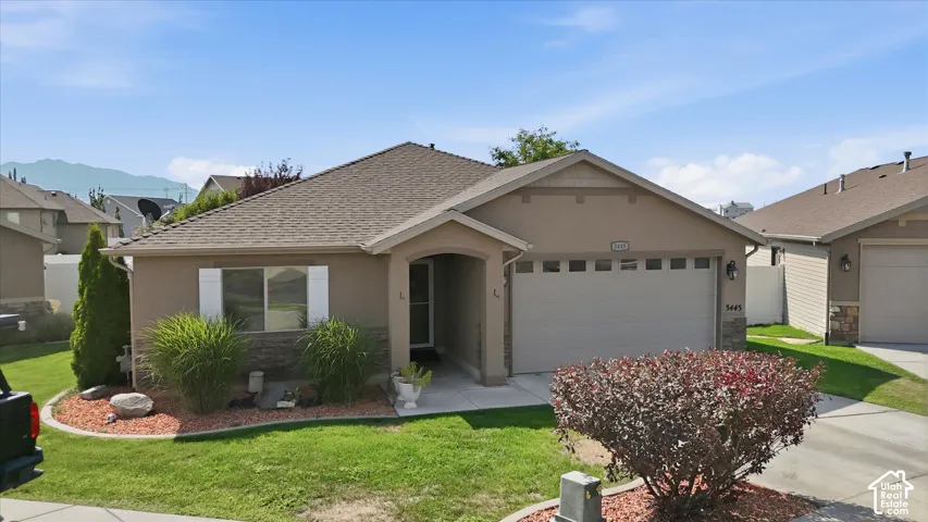 Single-story stucco exterior with stone accents, attached two-car garage, and established front landscaping