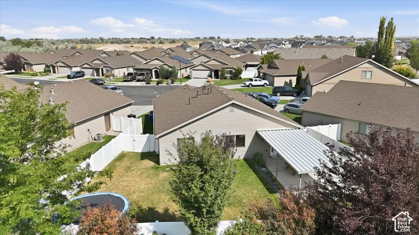 Fenced backyard with mature trees and a covered patio area