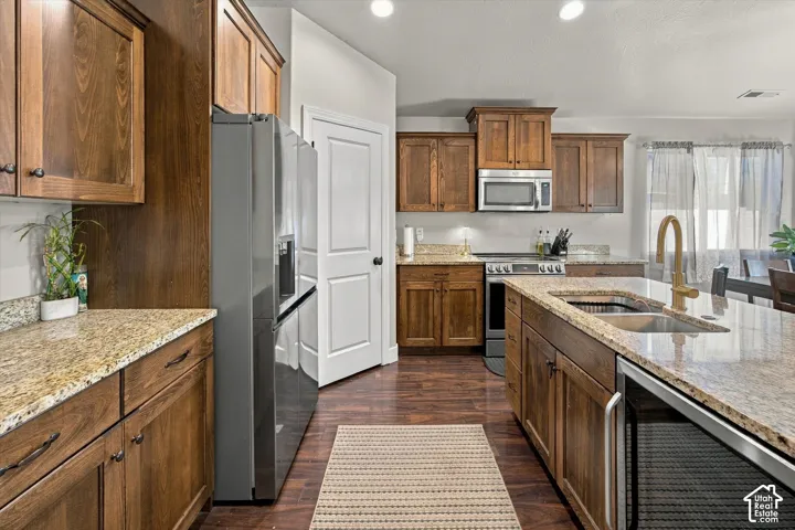 Kitchen featuring wood cabinetry, granite countertops, stainless steel appliances, and wood-finish flooring