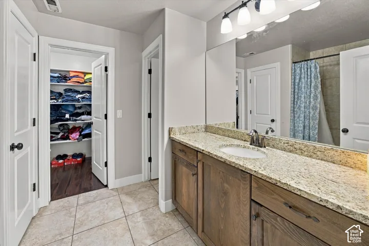 Bathroom featuring a single vanity with granite countertop, integrated sink, and wood-finish cabinetry