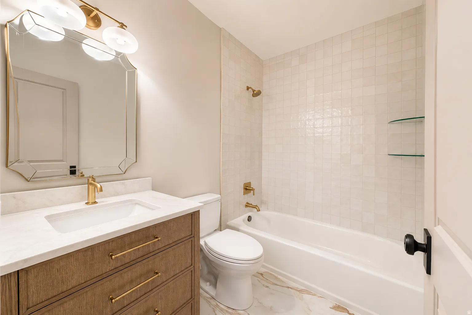 Beautiful renovated bathroom with a wood vanity, tile floor and backsplash and lighting.
