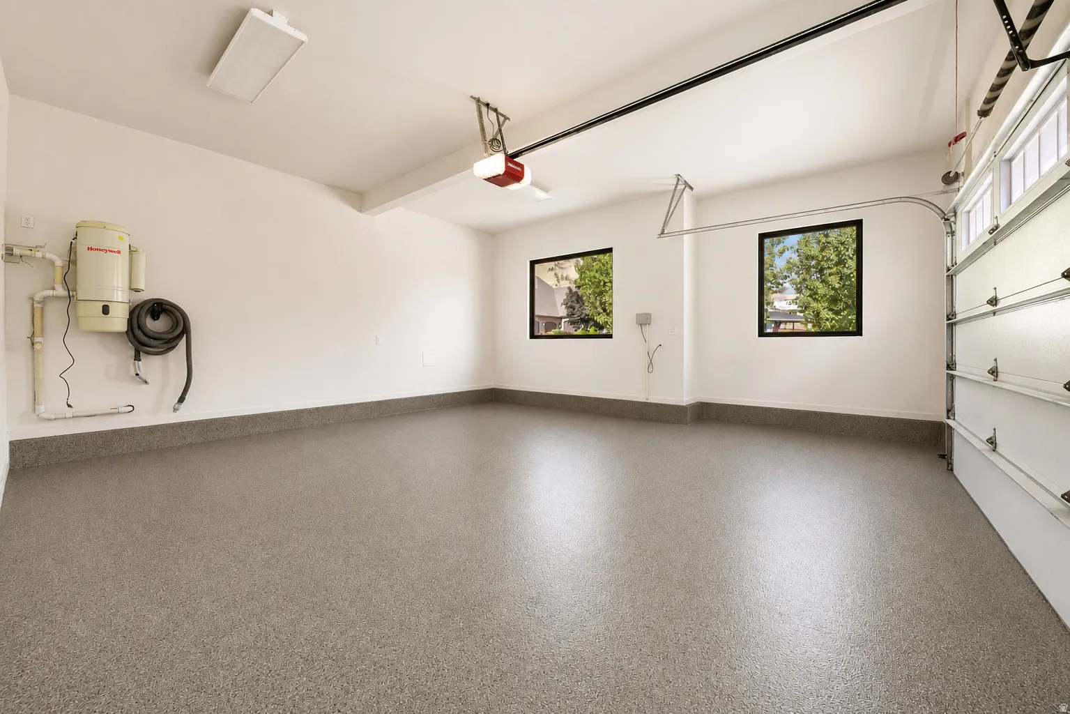 Two car garage with newly epoxy-coated flooring and natural lighting from two large windows.