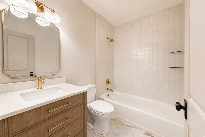 Beautiful renovated bathroom with a wood vanity, tile floor and backsplash and lighting.