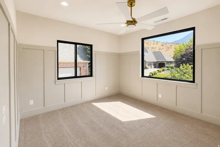 Bedroom 3 with new board and batten wainscoting, recessed lighting, ceiling fan, new carpeting and windows.