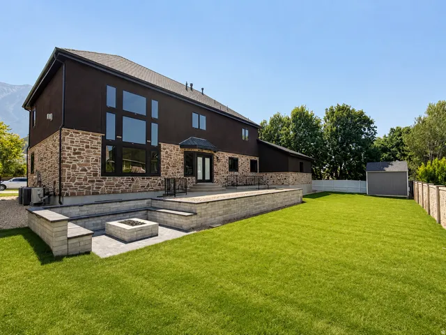 Spacious backyard featuring a large paved patio with built-in seating, a fire pit, and a separate storage shed