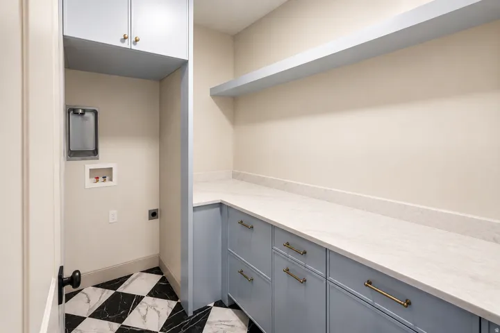 Brand new laundry space featuring built in cabinetry storage and fun checkerboard tile flooring.
