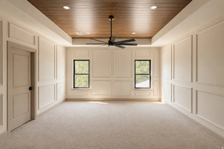 Primary Suite with wood-finish paneling in tray ceiling, wall moldings, and a new ceiling fan.