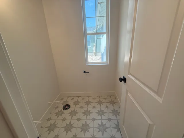 Patterned tile flooring, white interior door with black hardware, and a single pane window