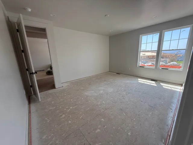 Recessed lighting, dual windows with grilles, white trim, and a paneled door with dark hardware