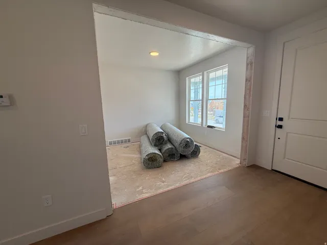 Wood-finish flooring, recessed lighting, and a white paneled door with black hardware