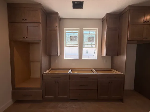 Brown wood-finish cabinetry, built-in appliance alcove, integrated drawer pulls, and dual windows