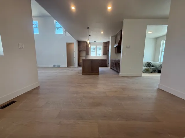 Open-concept layout featuring wood-finish flooring, recessed lighting, and a kitchen with warm-toned cabinetry