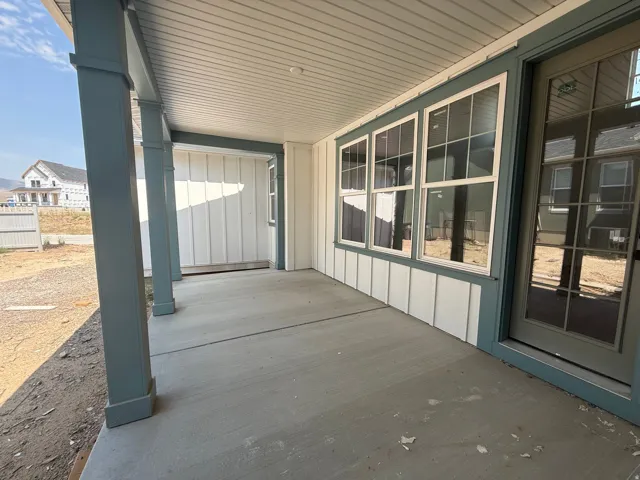 Covered porch with concrete flooring, vertical siding, multi-pane windows, and a full-light glass door