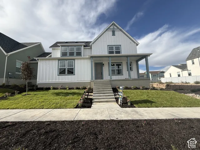 Modern farmhouse exterior with white board and batten siding, dark shingle roof, and a covered porch with light blue columns