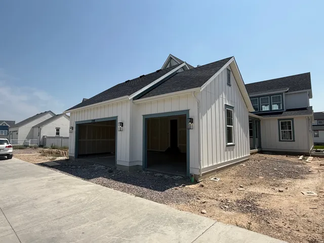 Two-car garage with vertical siding, exterior lighting fixtures, and a pitched roof