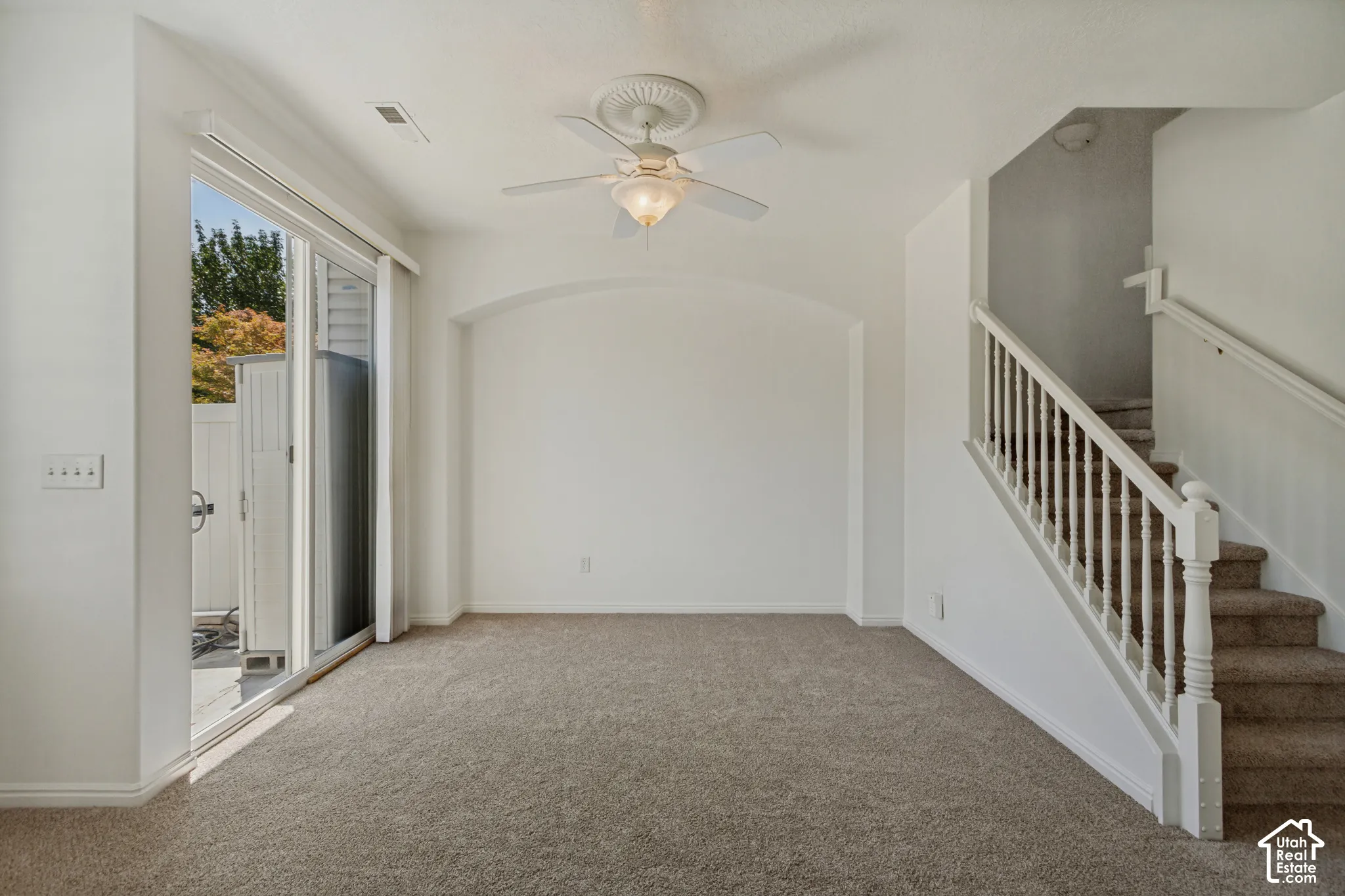 Neutral carpet flooring, white walls, and a ceiling fan with integrated lighting