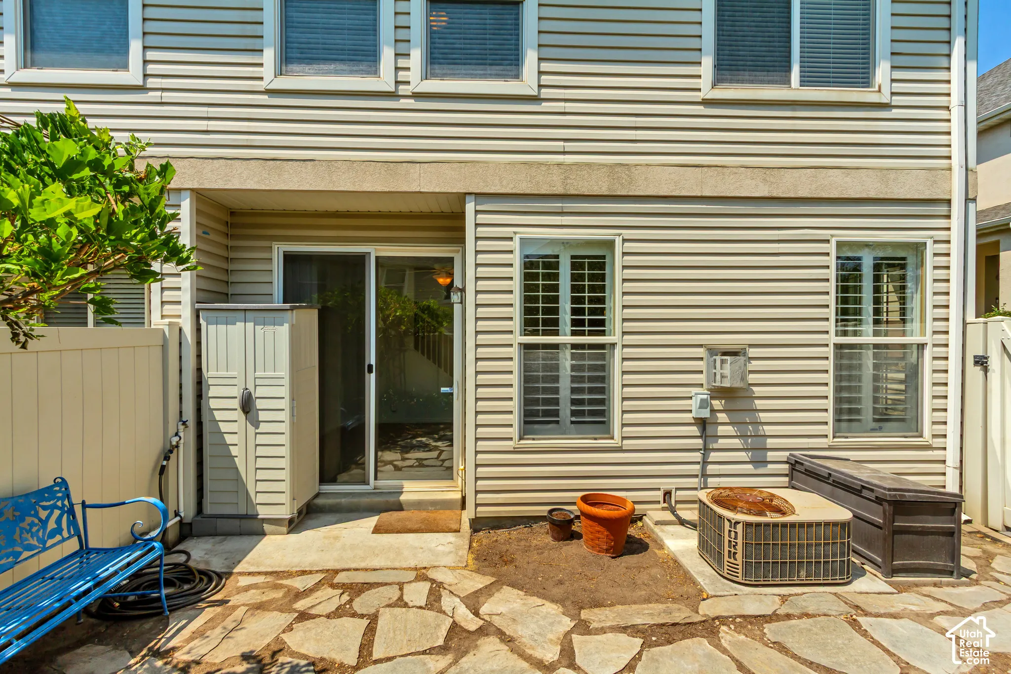 Flagstone patio with a sliding glass door entry, vinyl siding exterior, and privacy fencing