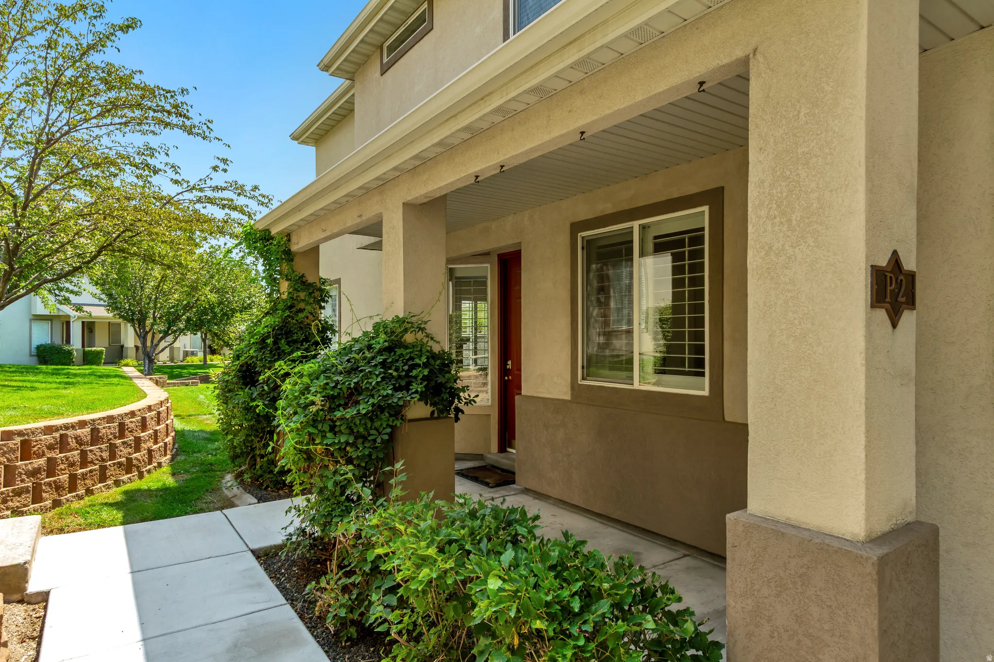 Covered entry with stucco exterior and concrete walkway