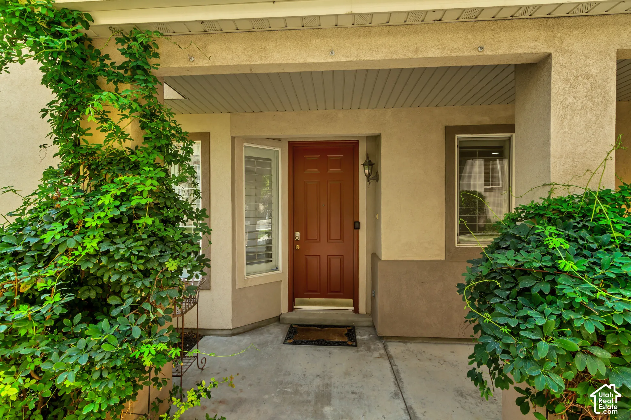 Covered entryway featuring a paneled door, exterior wall lantern, and concrete pathway