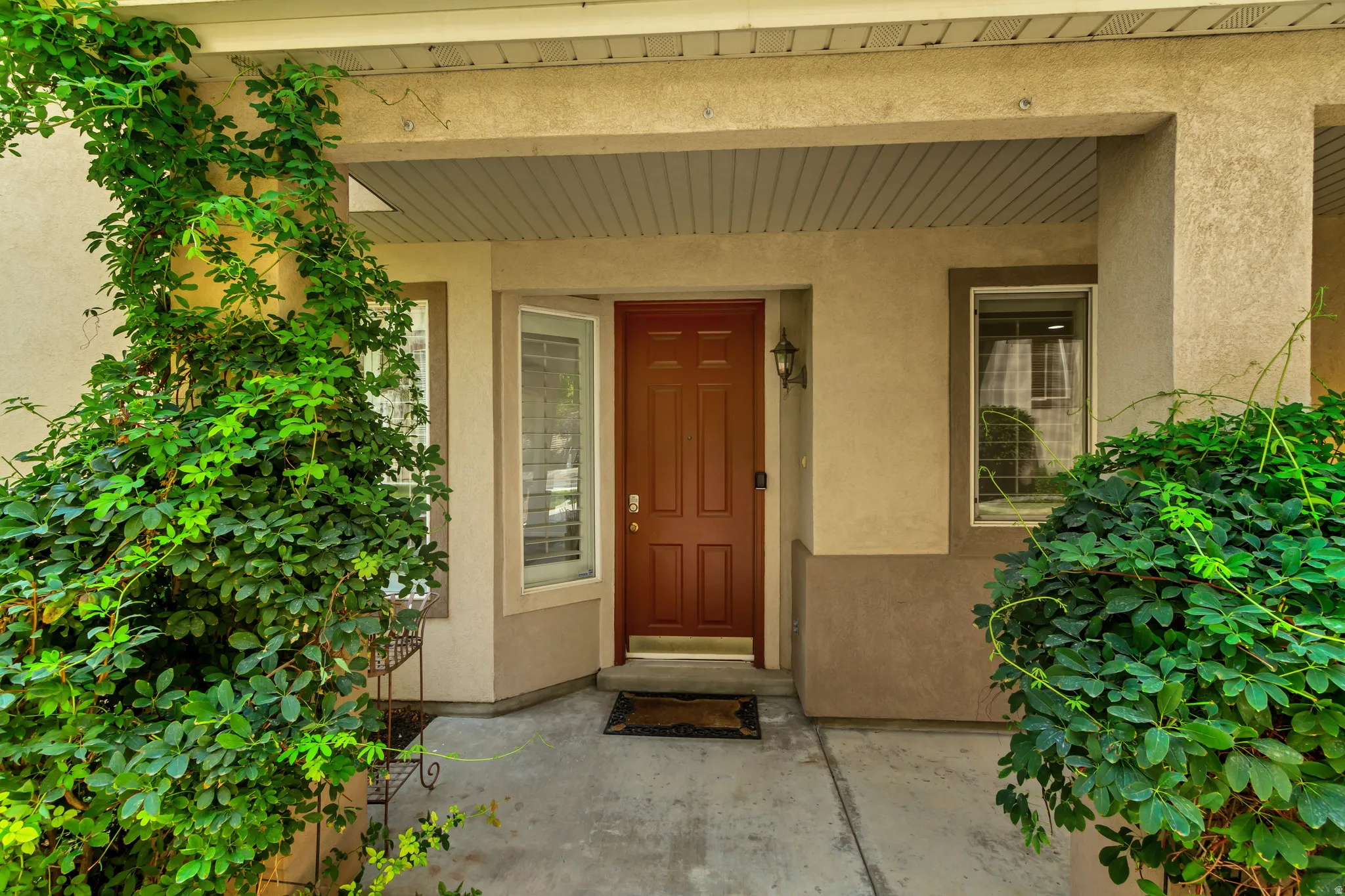 Covered entryway featuring a paneled door, exterior wall lantern, and concrete pathway