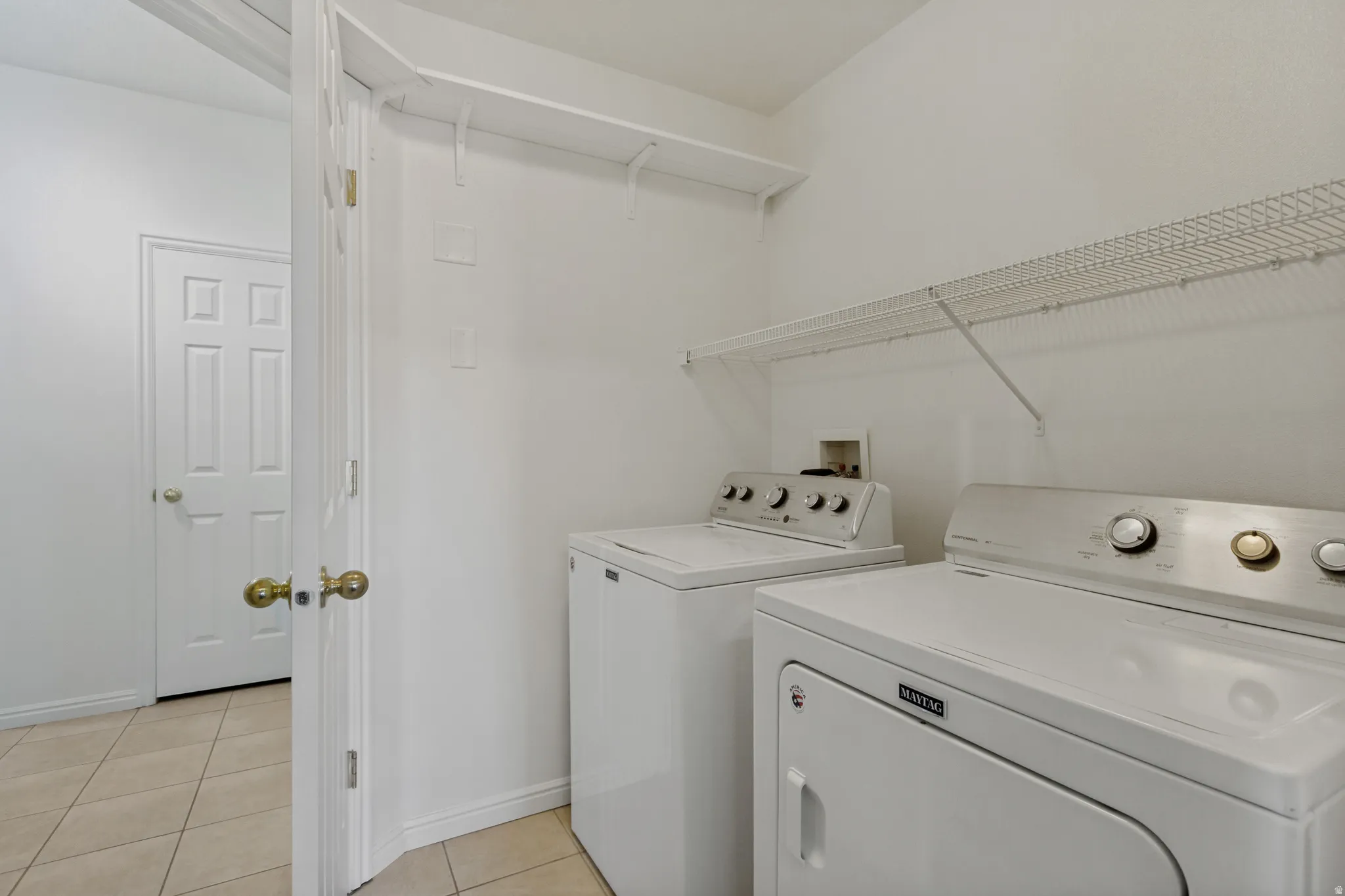 Laundry area featuring a top-load washing machine, front-load dryer, and wire shelving