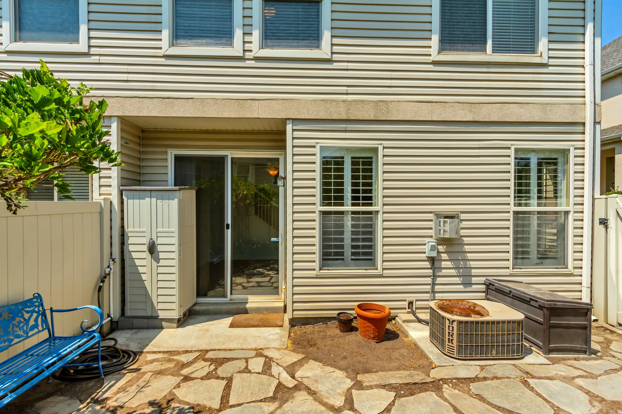 Flagstone patio with a sliding glass door entry, vinyl siding exterior, and privacy fencing