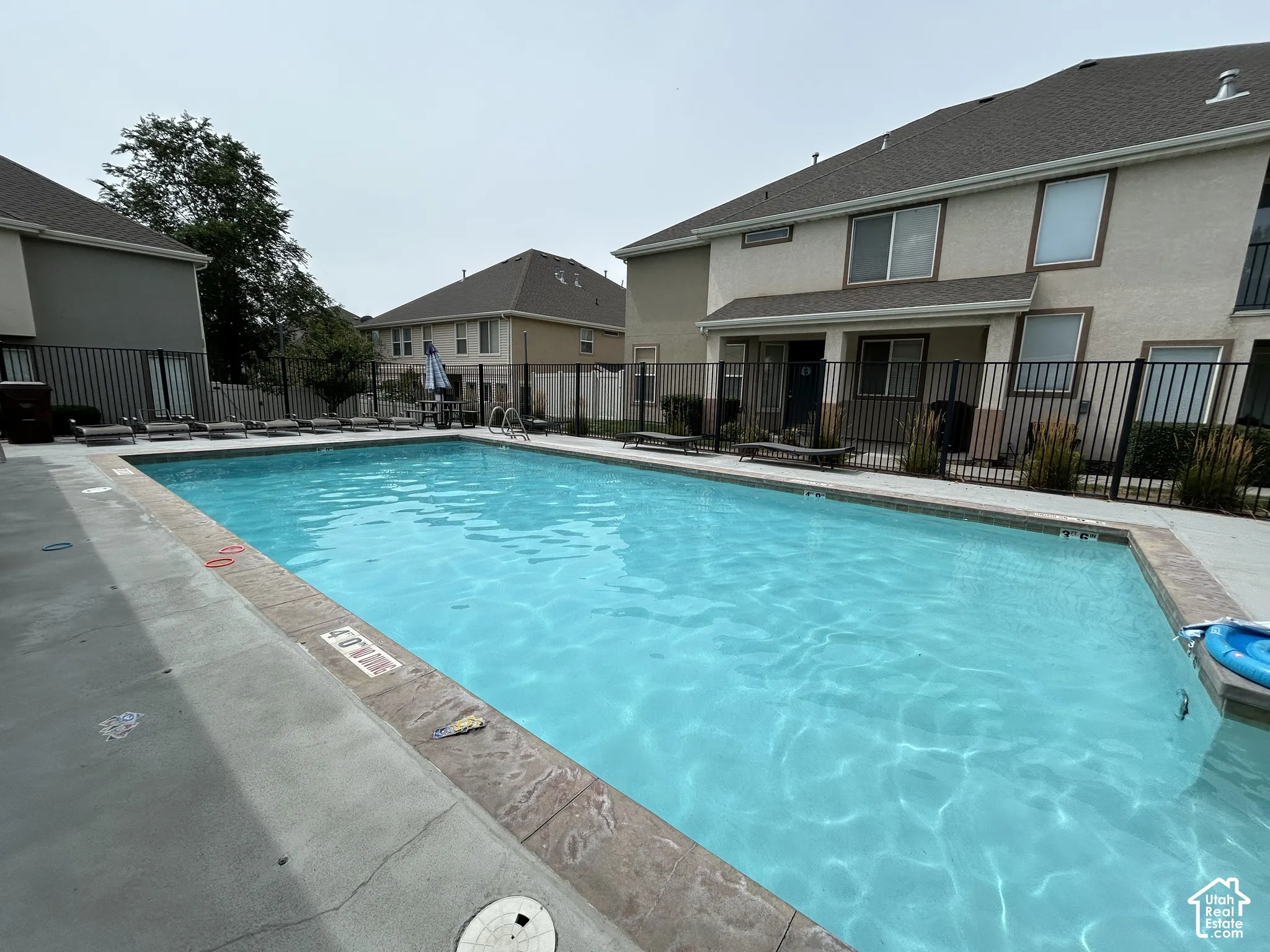 Rectangular swimming pool with concrete decking and a dark metal perimeter fence