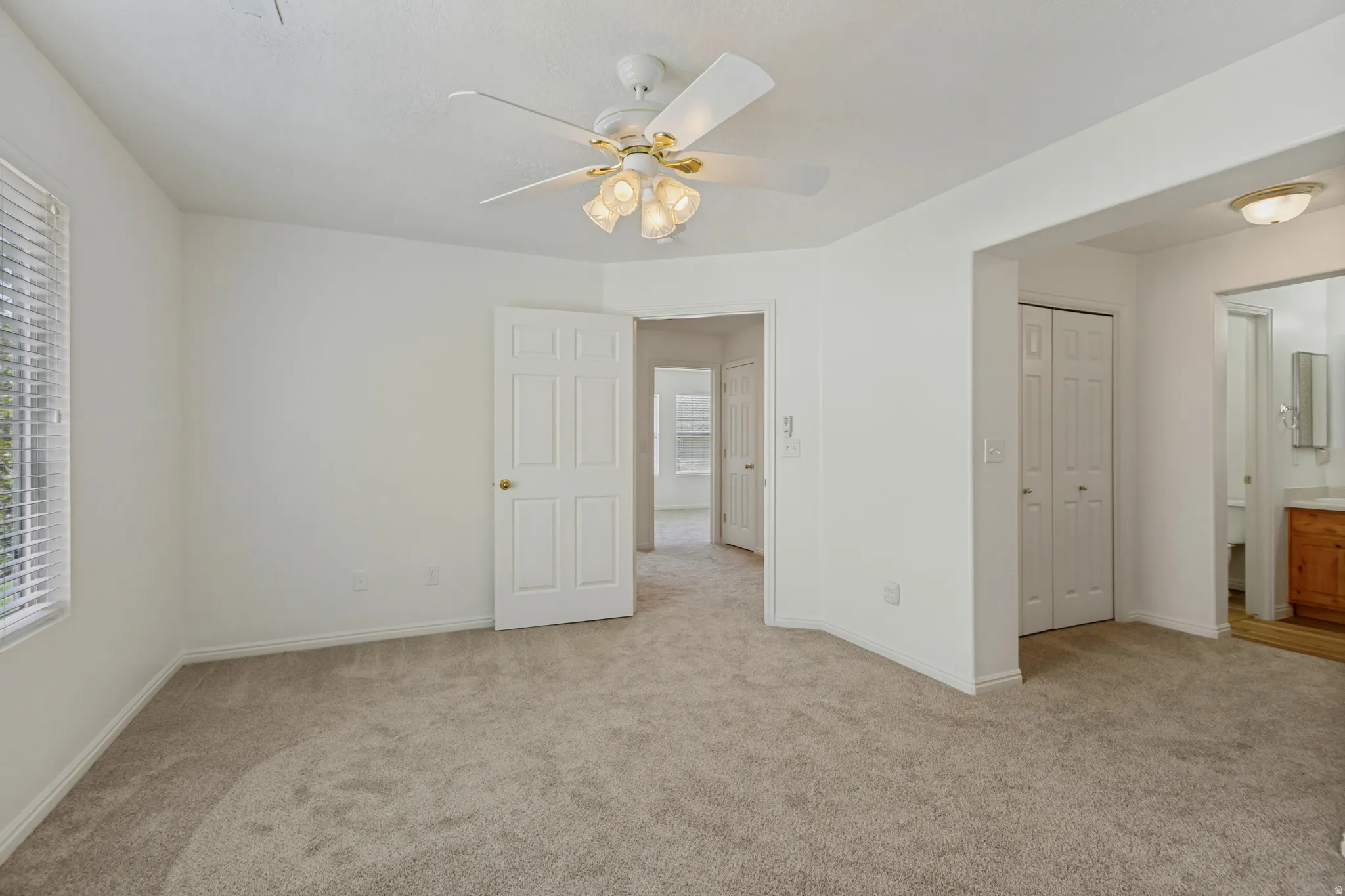 Spacious room with plush carpeting, ceiling fan with integrated lighting, and multiple paneled doors