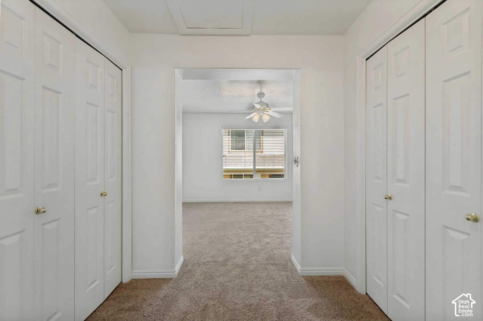 Plush carpet flooring, white bi-fold closet doors, brass door hardware, white window blinds, and a ceiling fan with integrated lighting