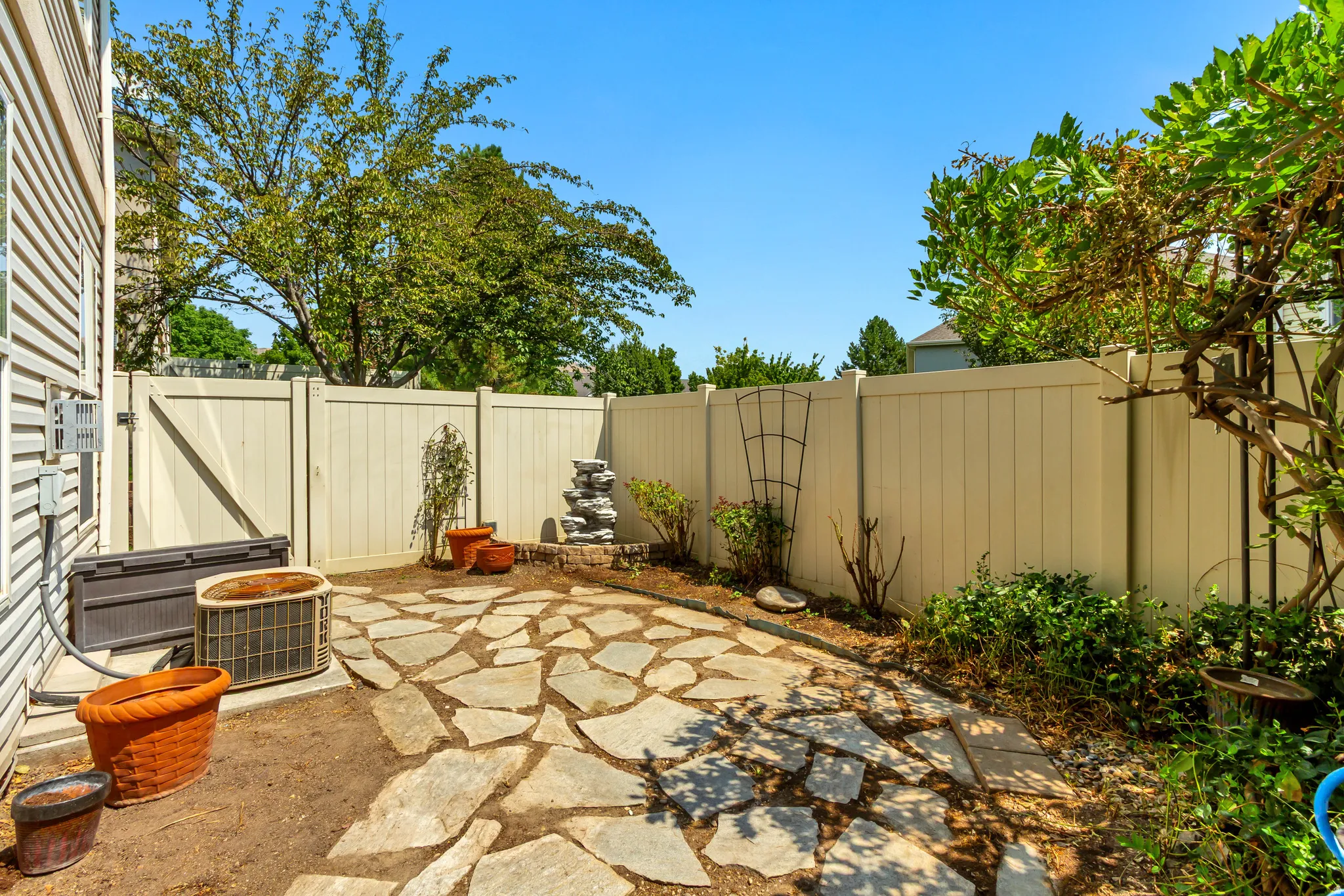 Flagstone patio area with a privacy fence and mature landscaping