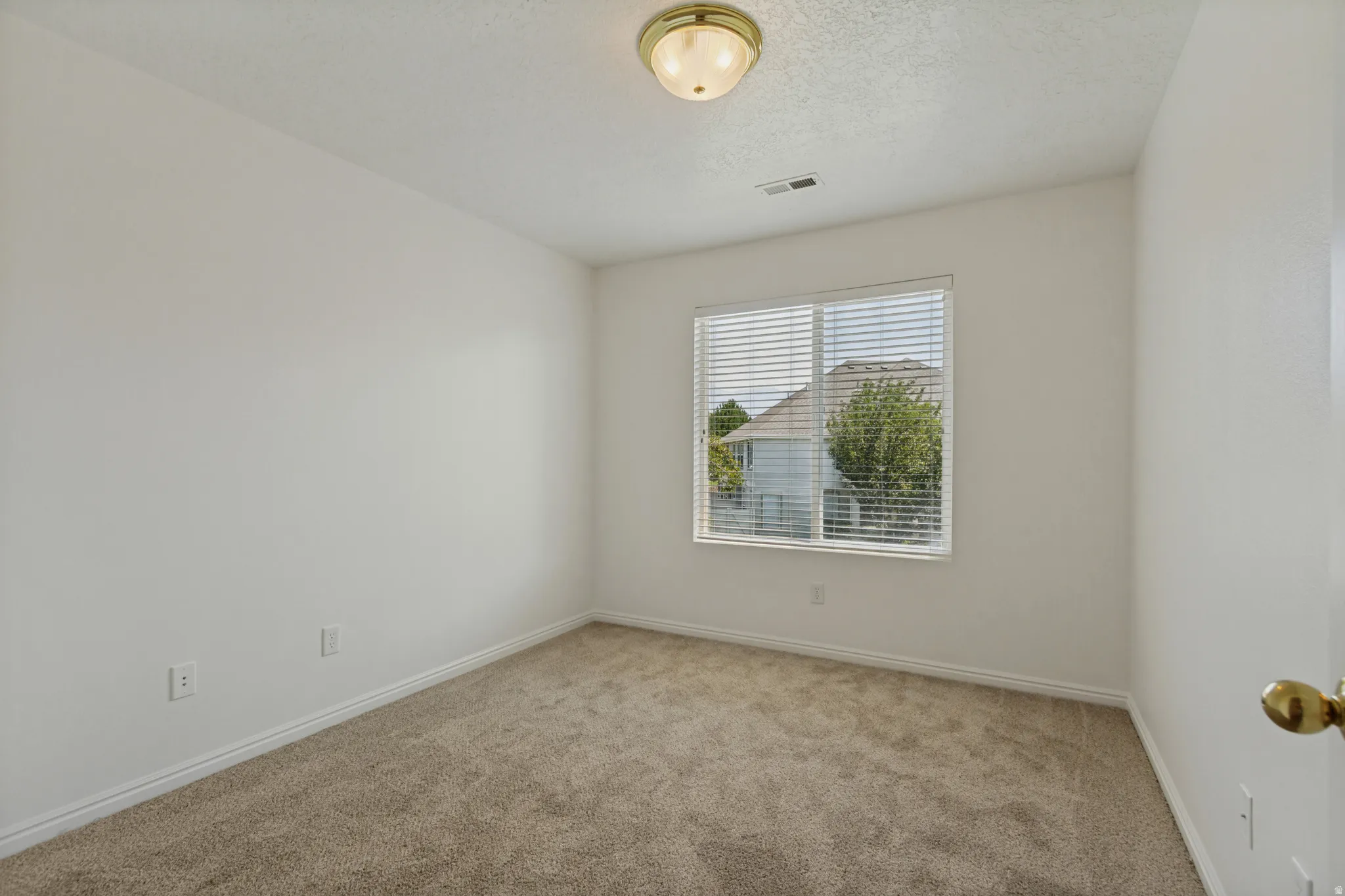 Neutral-toned carpeting, white painted walls, and a window with blinds