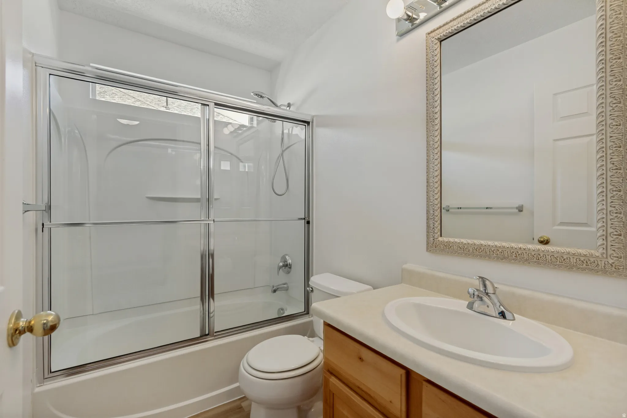 Bathroom featuring a built-in vanity with wood-finish cabinetry, an oval undermount sink, and a framed mirror