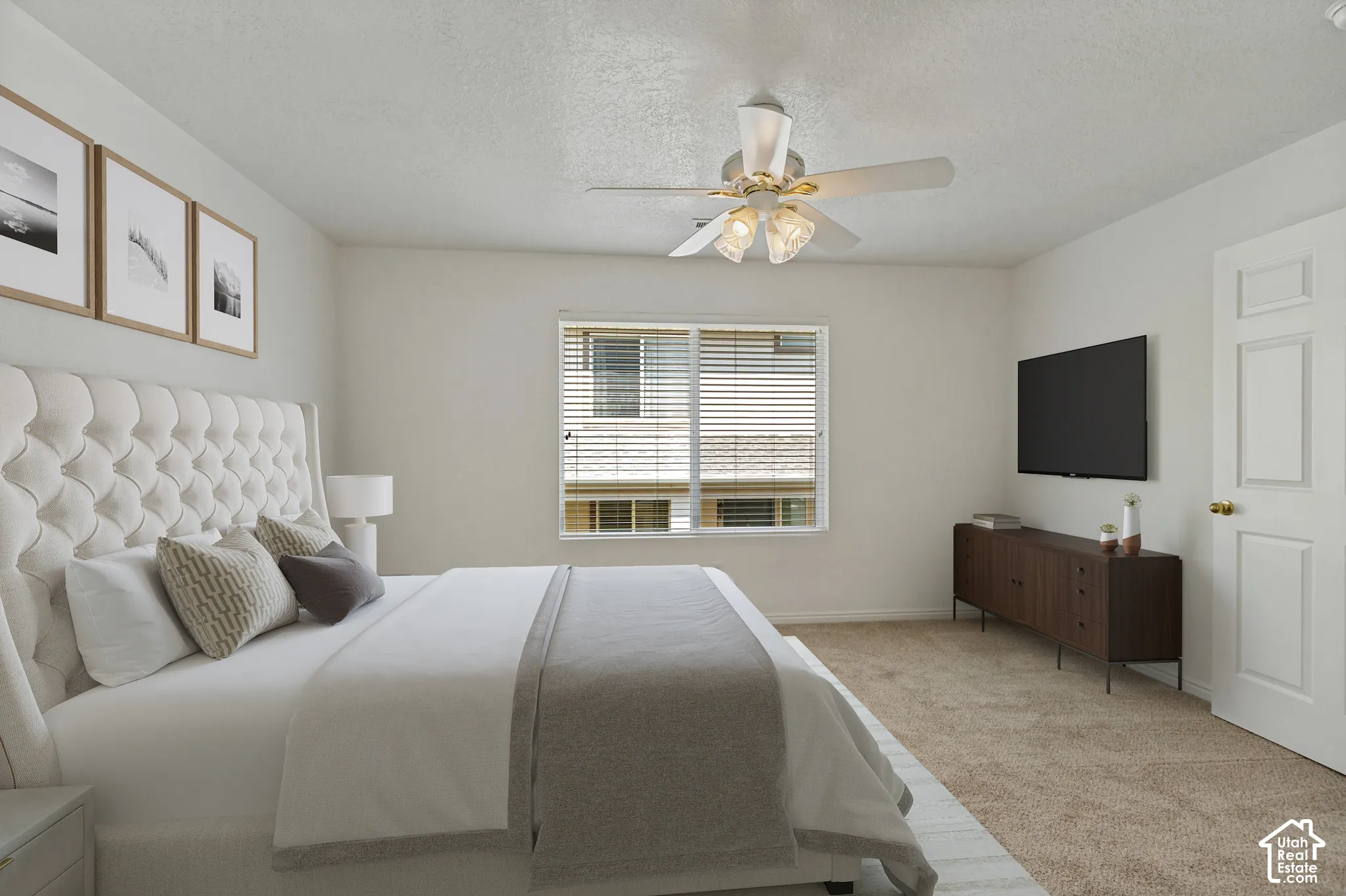 Carpeted bedroom with a window, ceiling fan with light fixture, and a white paneled door